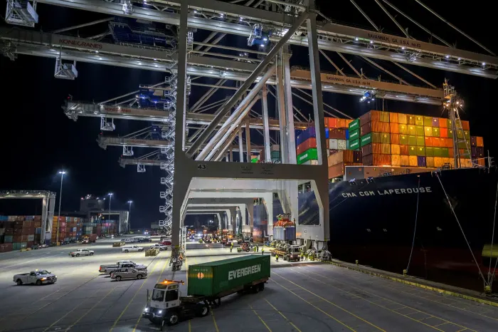 Five ship to shore cranes and gangs of longshoremen work to load and unload a container ship at Savannah, Georgia